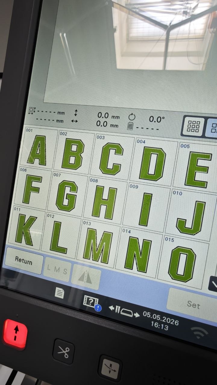 Display der Stickmaschine zeigt grüne Buchstaben A bis O als Schriftauswahl