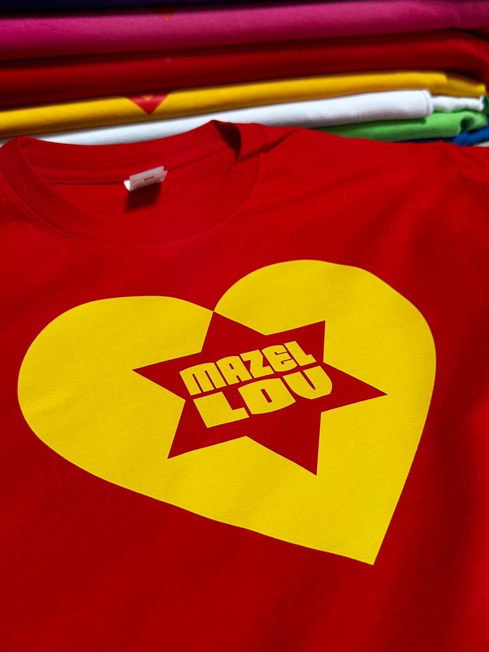 Rotes T Shirt mit gelbem Mazel Lov Logo bedruckt im flächigen Direktdruck
