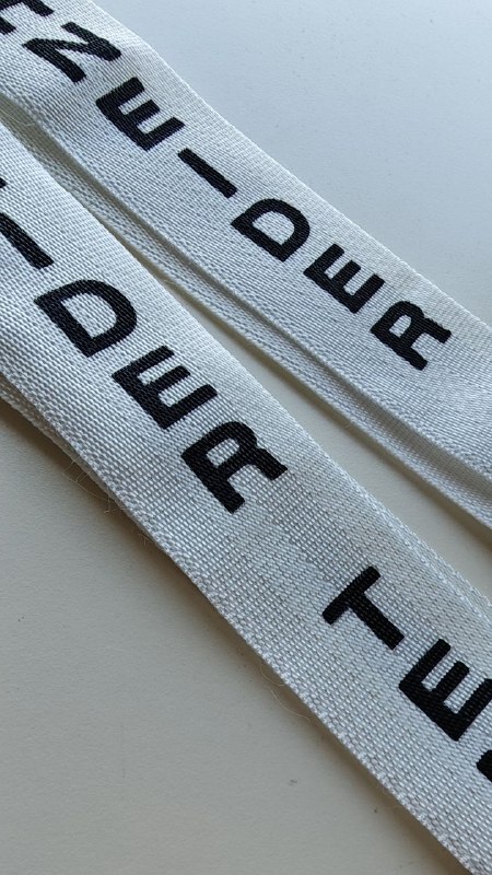 Siebdruck in Wien: weiße Stoffgurte bedruckt mit präzisem schwarzem Schriftzug